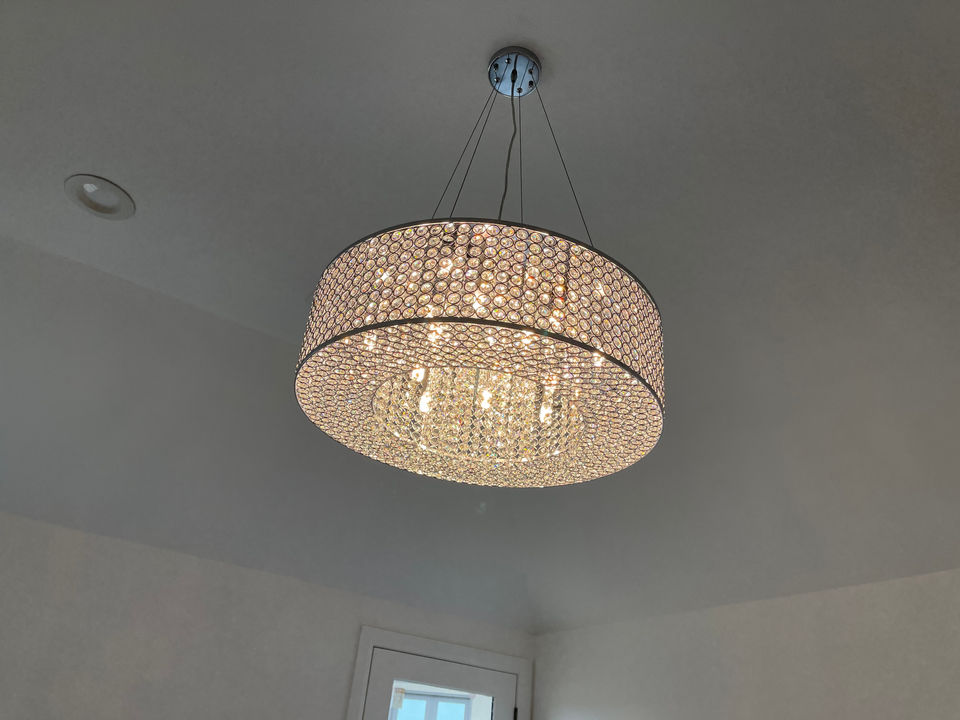 Round crystal chandelier suspended from a residential ceiling