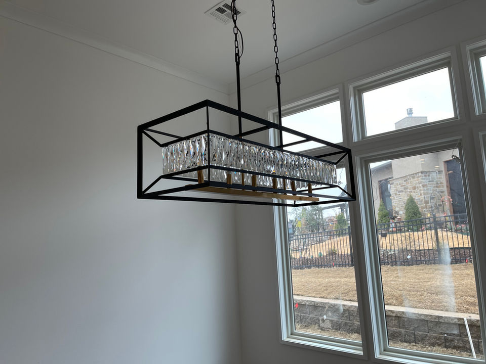 Rectangular black pendant fixture beside bright dining room windows