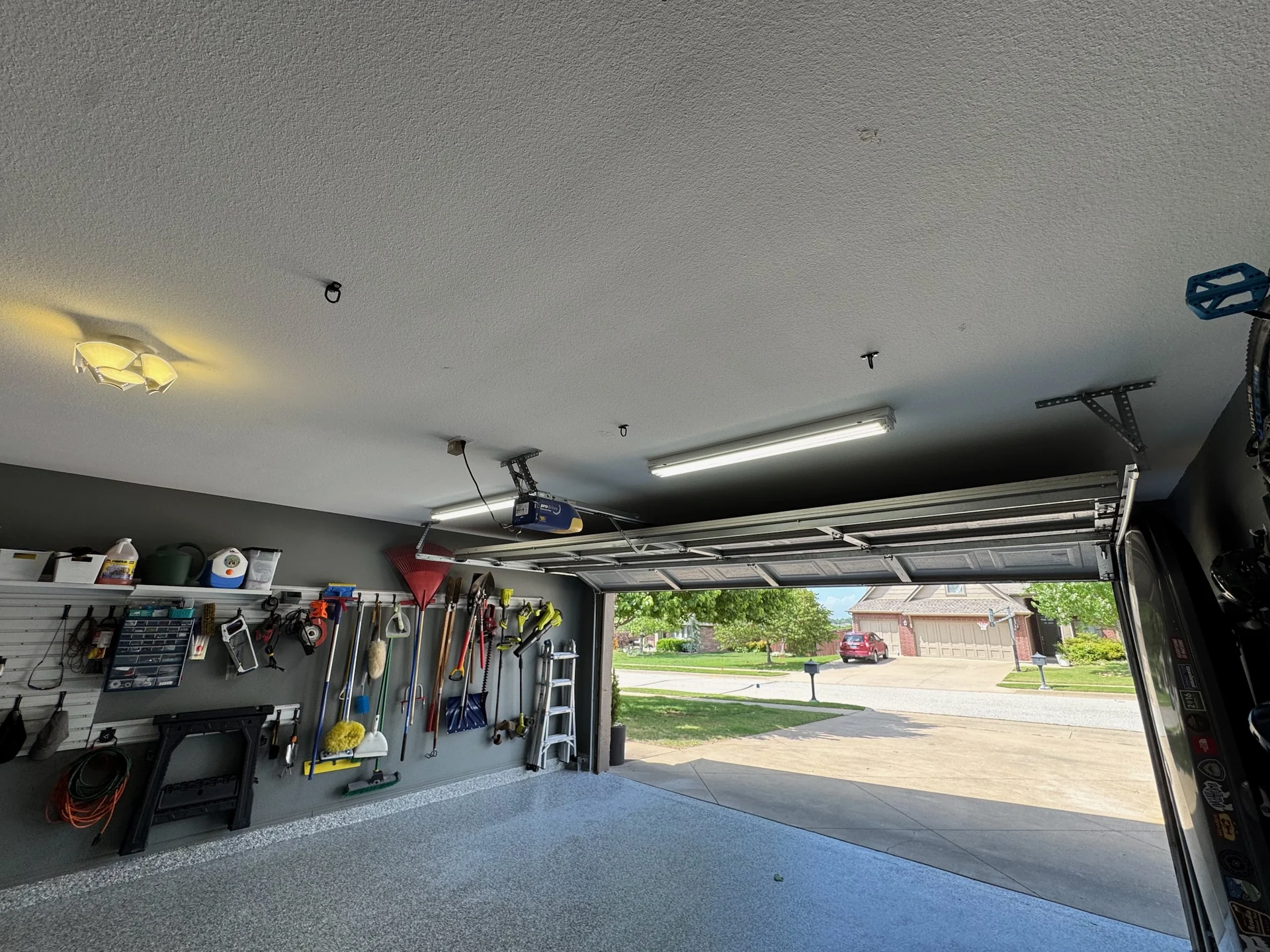 Illuminated linear garage ceiling fixtures above an open garage door and organized storage