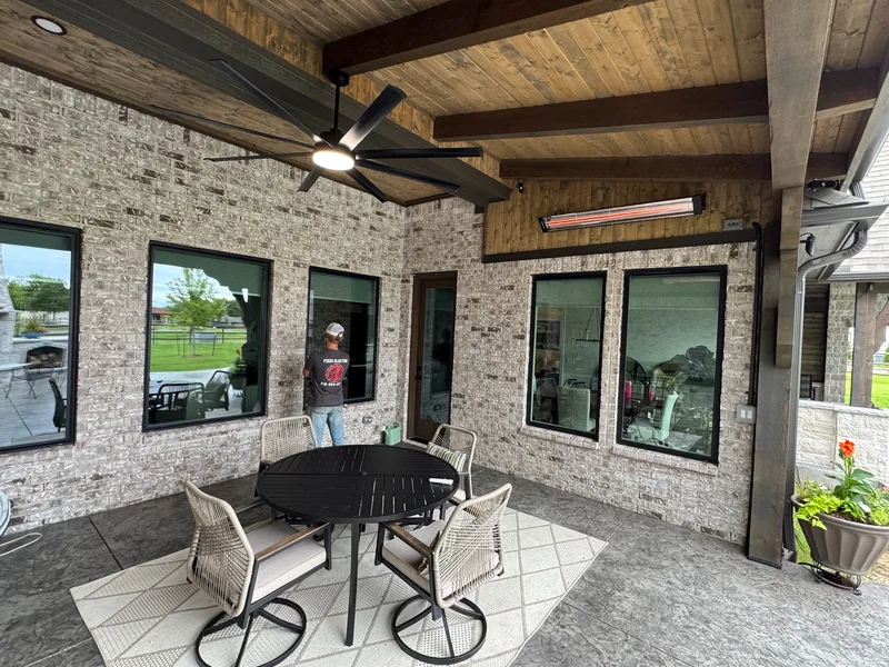 Glowing radiant heater and illuminated ceiling fan above a covered patio dining area