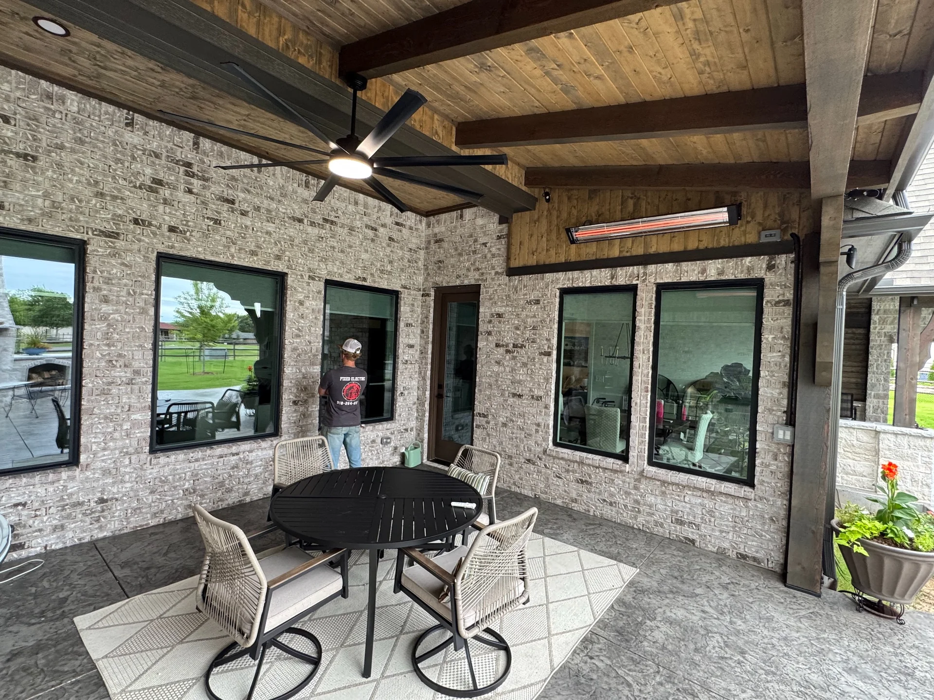 Glowing patio heater and ceiling fan above a timber-covered outdoor dining area