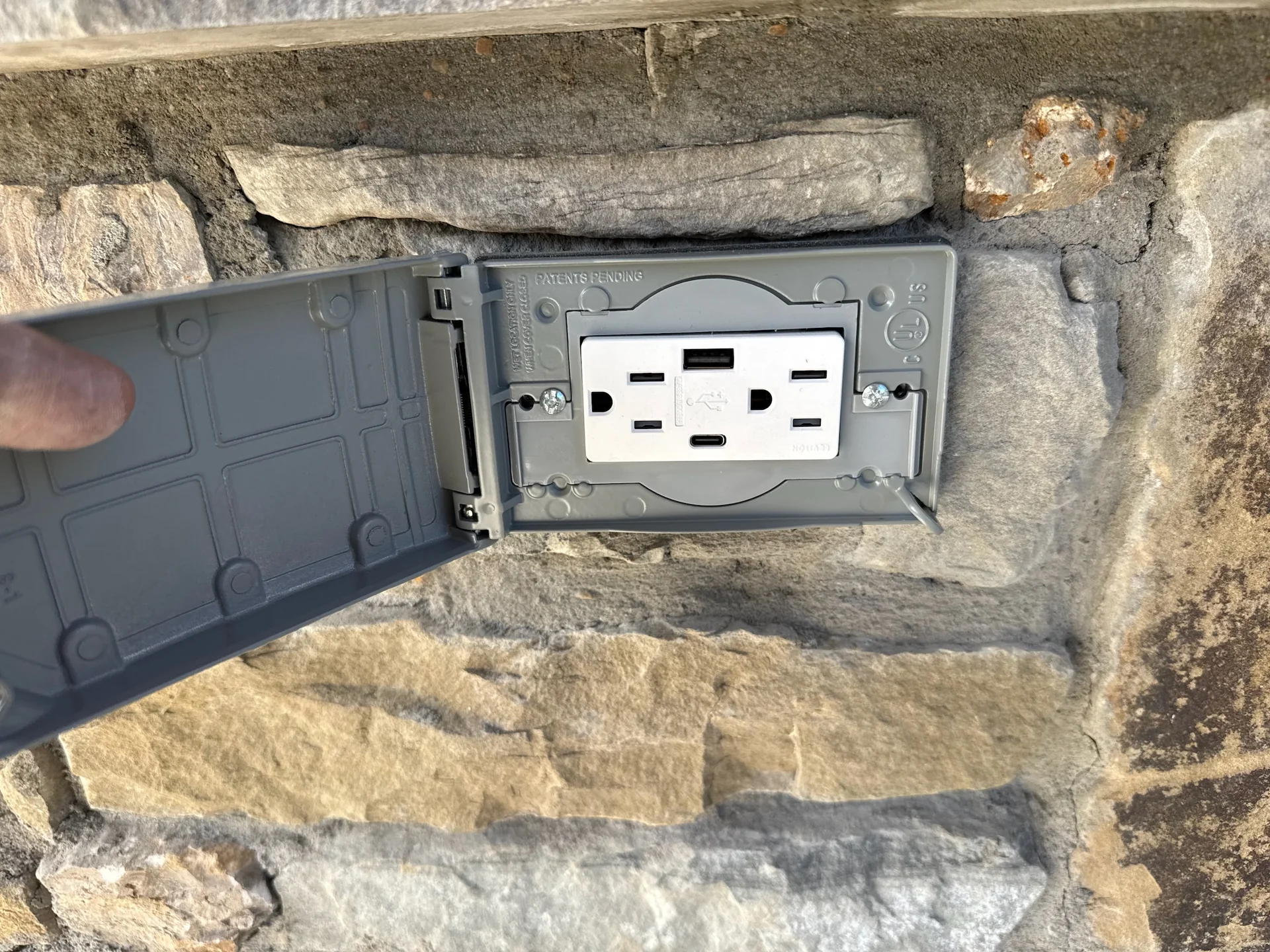 Close-up of a covered outdoor receptacle installed in a stone wall