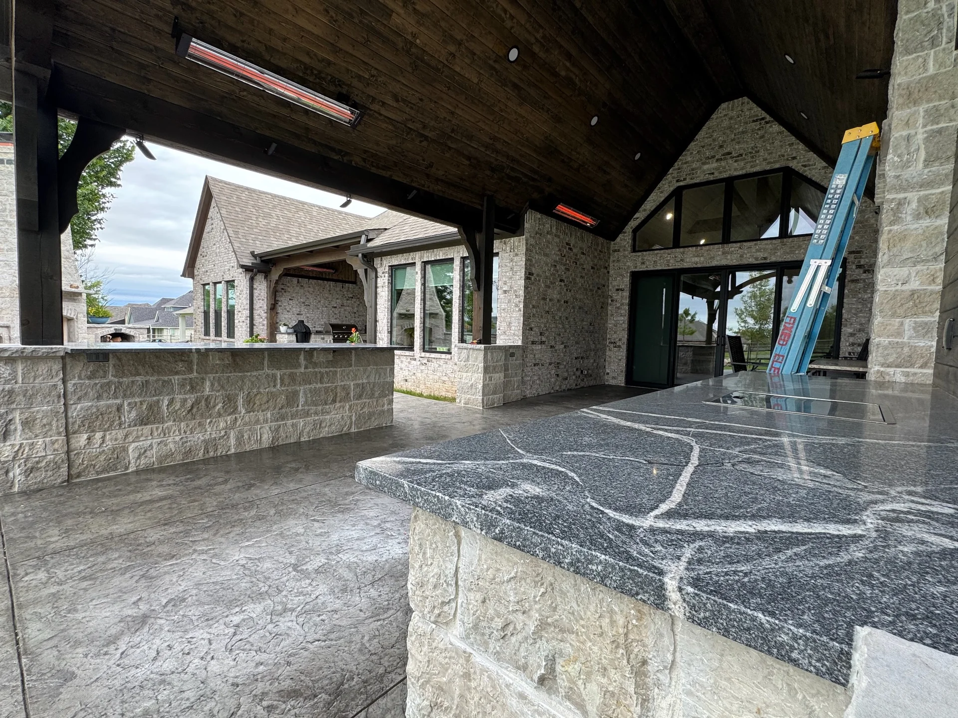 Outdoor bar beneath a vaulted timber patio roof with mounted heaters