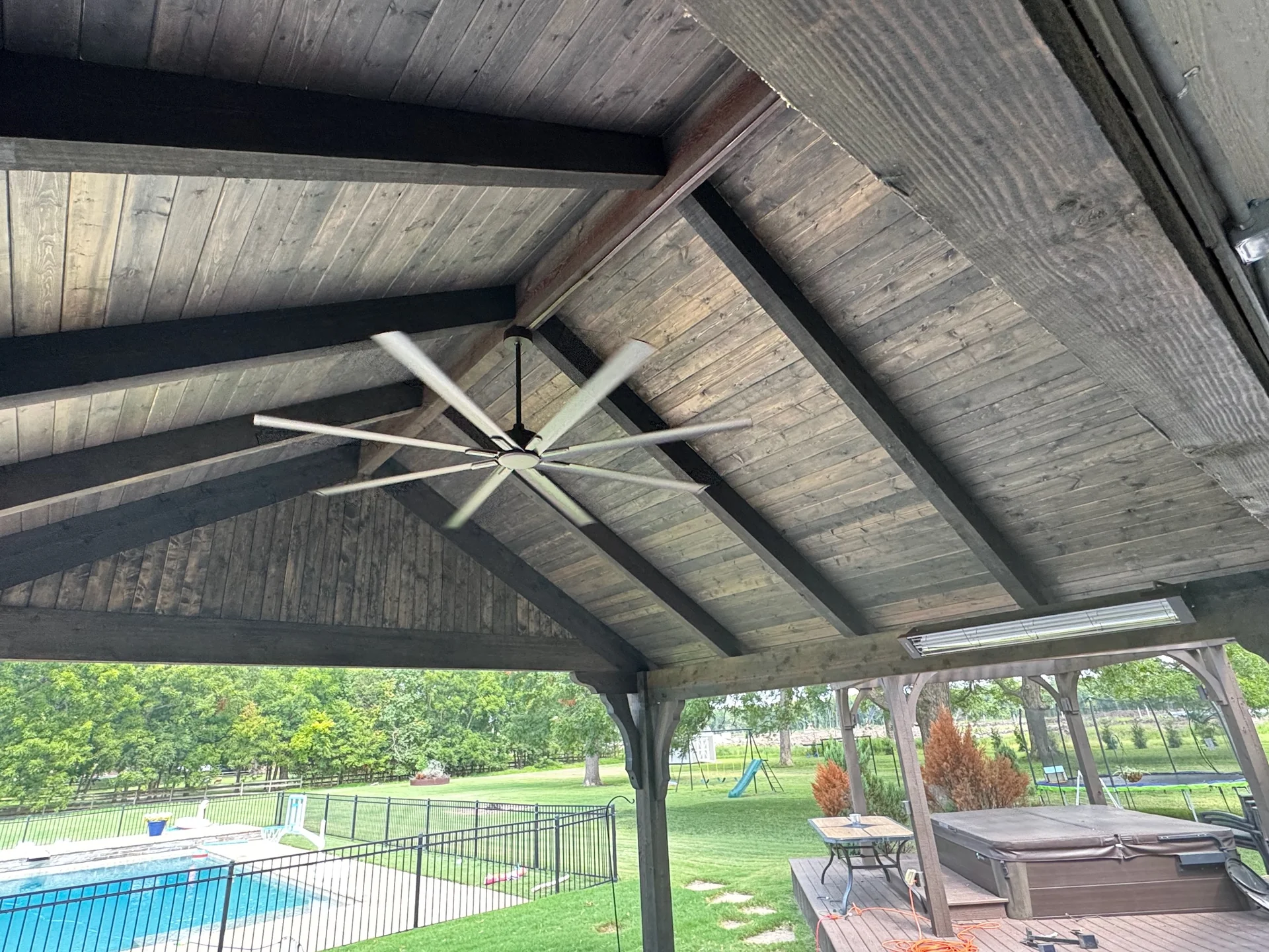 Ceiling fan installed among exposed timber beams on a covered patio