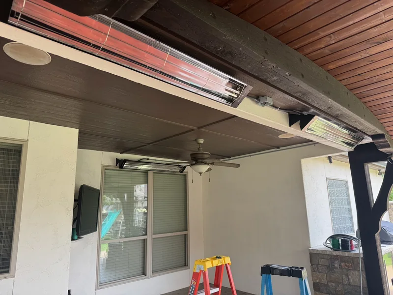 Radiant patio heaters glowing red beneath a covered patio ceiling