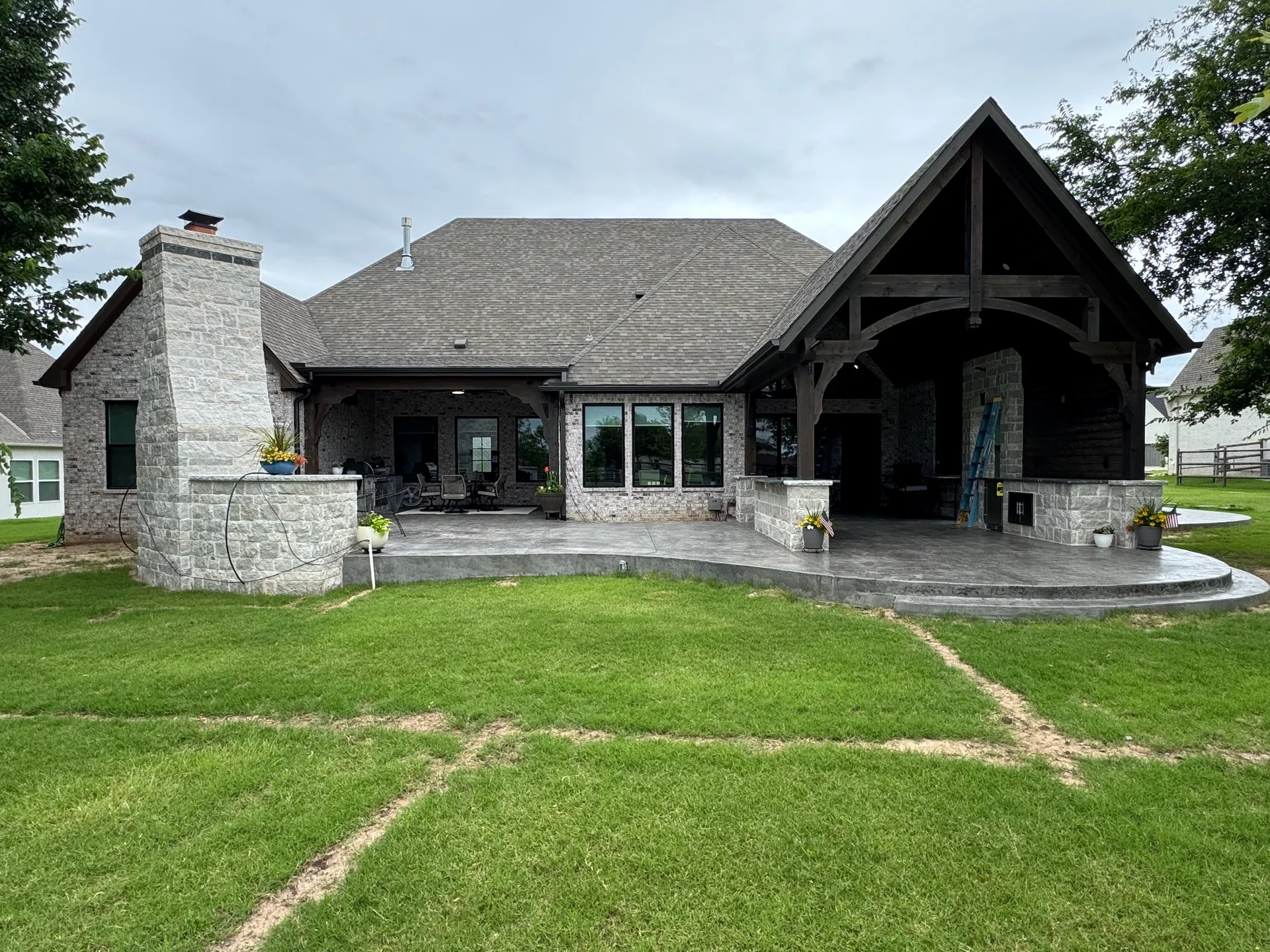 Wide exterior view of a timber covered patio attached to a brick home